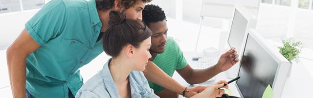 Two men and a woman look at a computer screen.