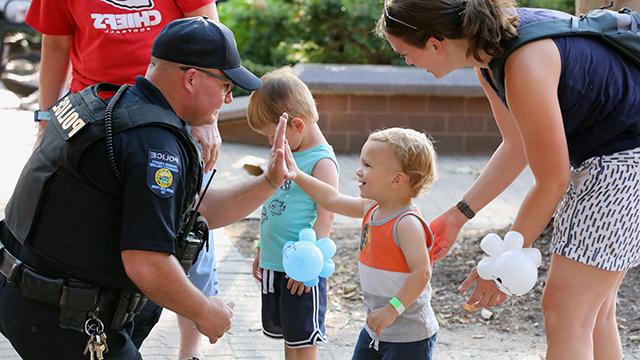 Police officer chatting with young children visiting campus